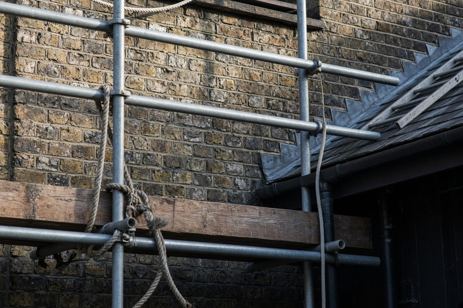 Scaffolding tubes against a brick house wall